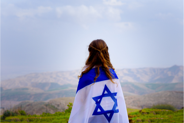An Israeli girl stands still, wrapped in a flag (Shutterstock.com)
